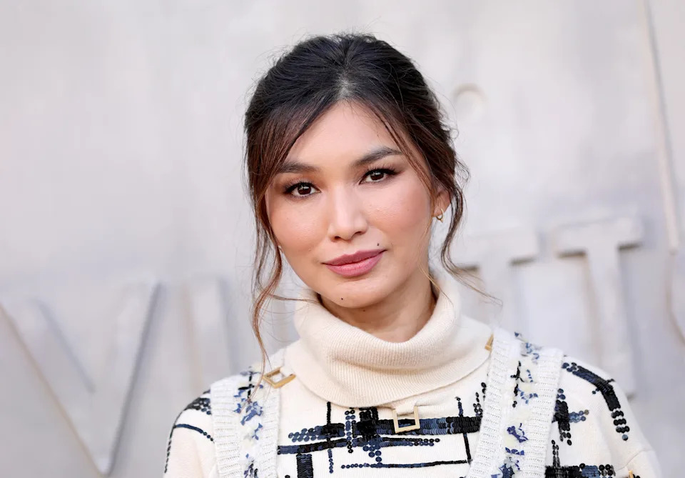 Person posing in a chic sweater with modern, artistic patterns and a high neckline. Their hair is styled in an updo