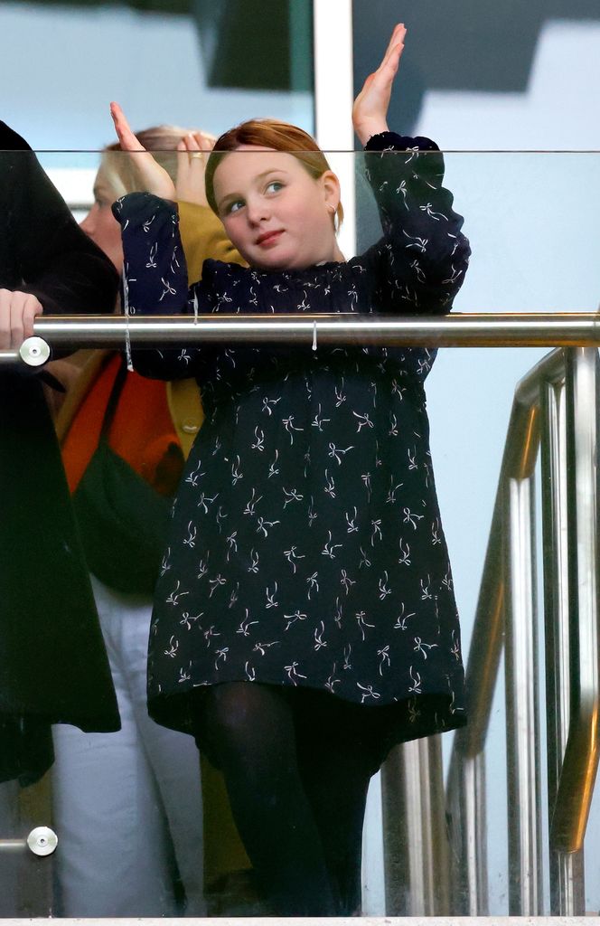 Mia with arms raised in navy dress