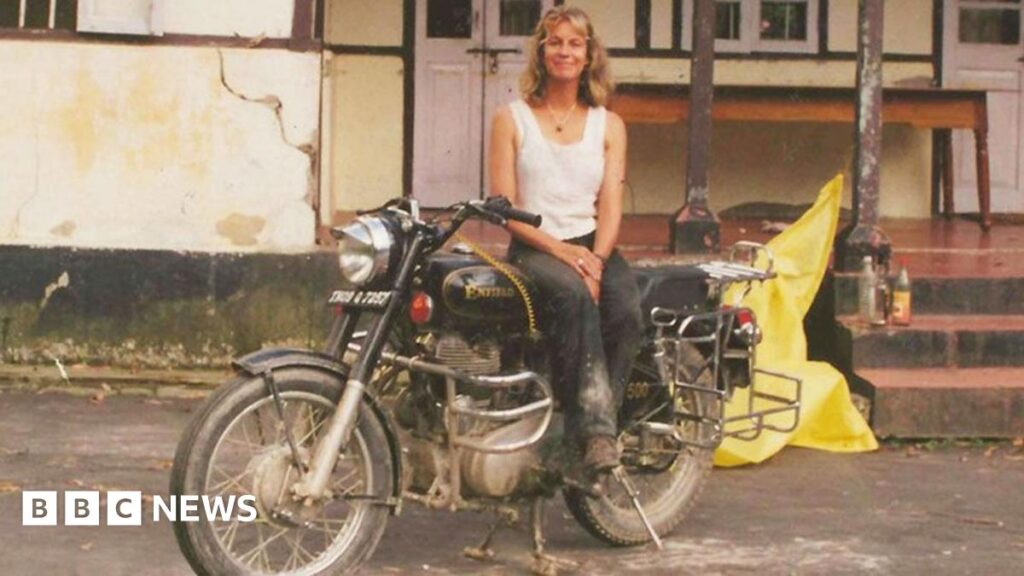 Travelling with a man I’d known for two days changed my life forever Jacqui Furneaux sitting on her motorbike smiling outside a rundown house on her travels in India
