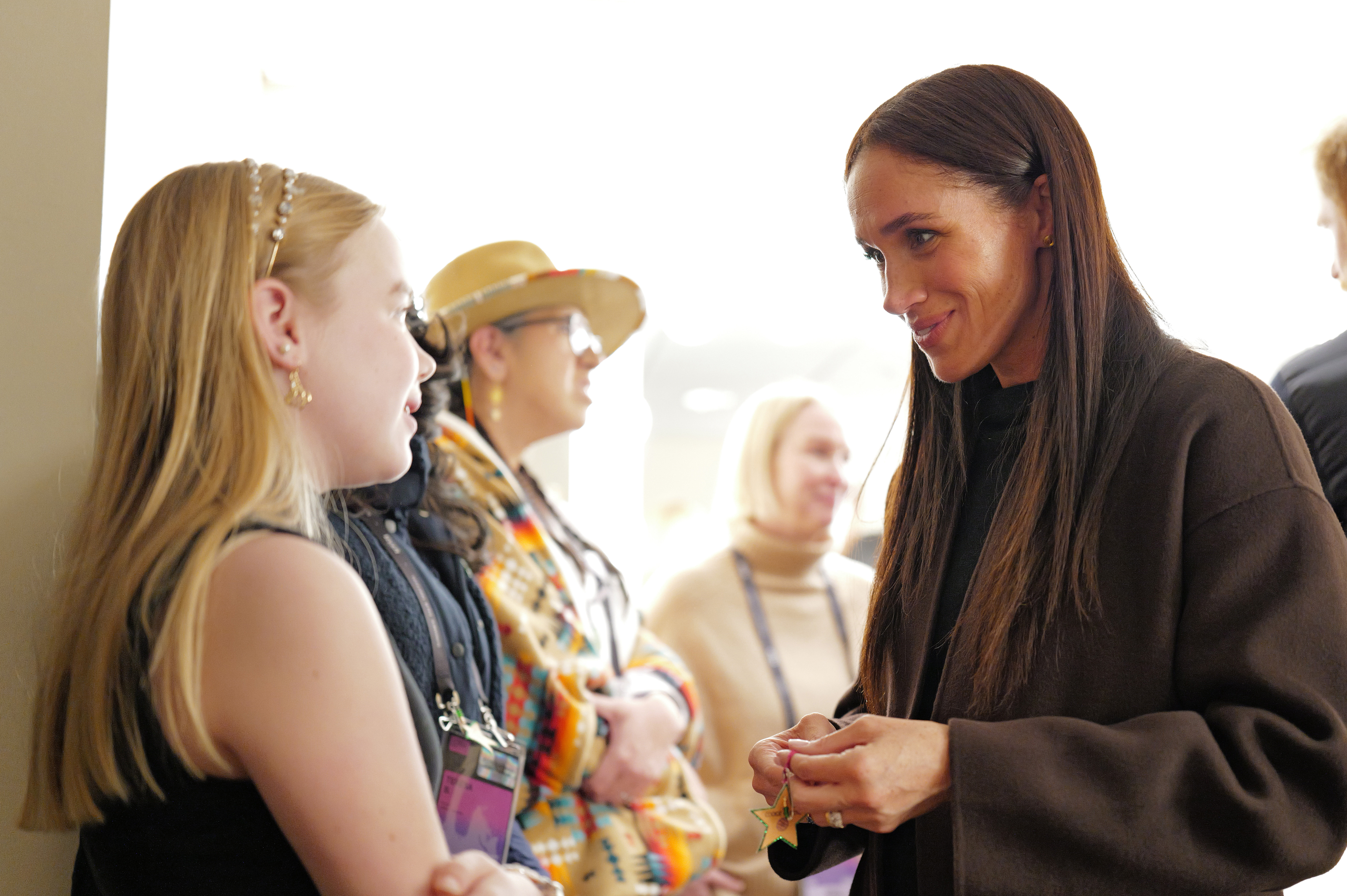 Meghan Markle poses wearing Mother black bootcut jeans and black sweater, and a brown cashmere coat, at the Salt Lake City celebration and premiere of "Cookie Queens" at Sundance Film Festival on January 24, 2026 in Salt Lake City, Utah