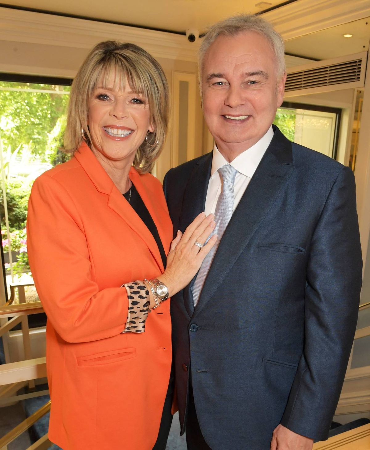 An adult male and an adult female are standing next to each other, smiling and looking at the camera. They are dressed in formal attire, suggesting a professional or formal event.