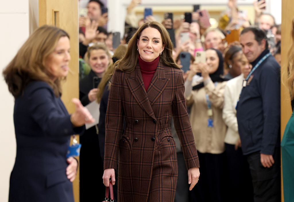 The Princess of Wales during a visit to The Royal Marsden Hospital wearing a brown check coat with red turtleneck and matching handbag