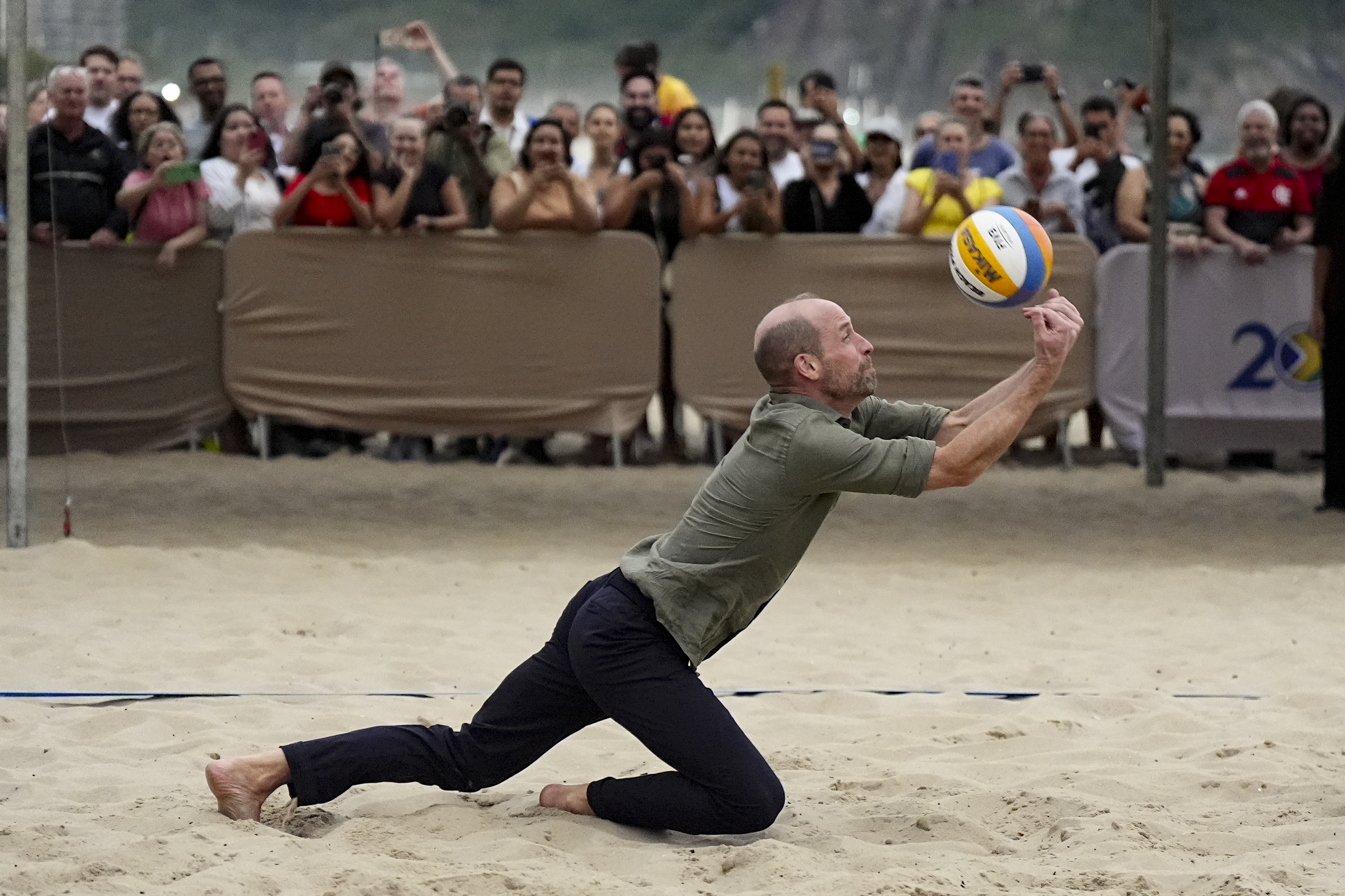 Prince of Wales throws himself on to the sand to reach a volleyball