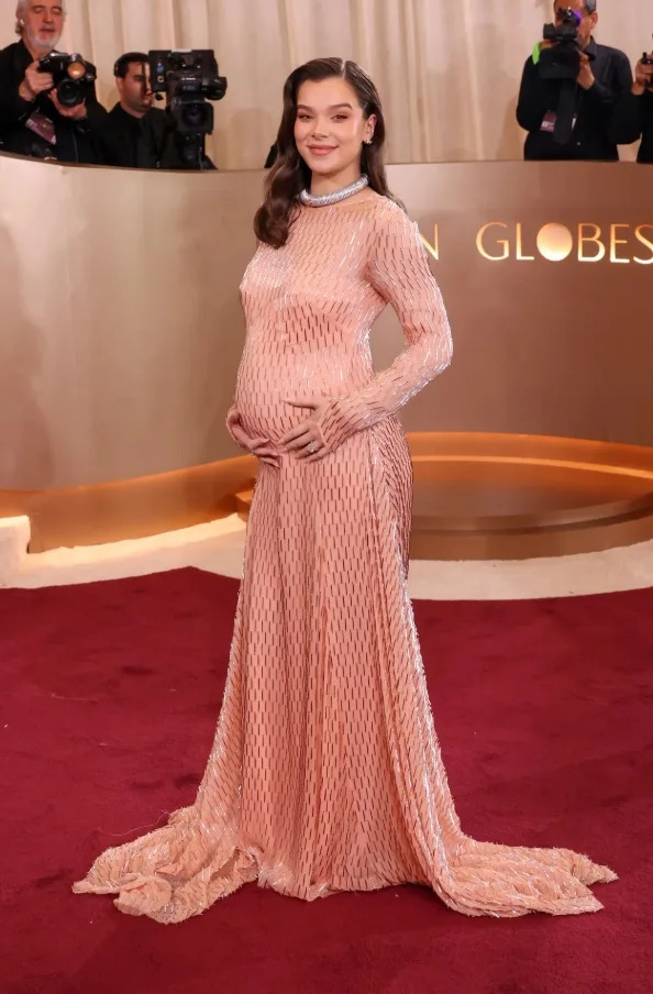 Hailee Steinfeld posing on the red carpet in a soft pink fitted gown while pregnant at the 2026 Golden Globes.