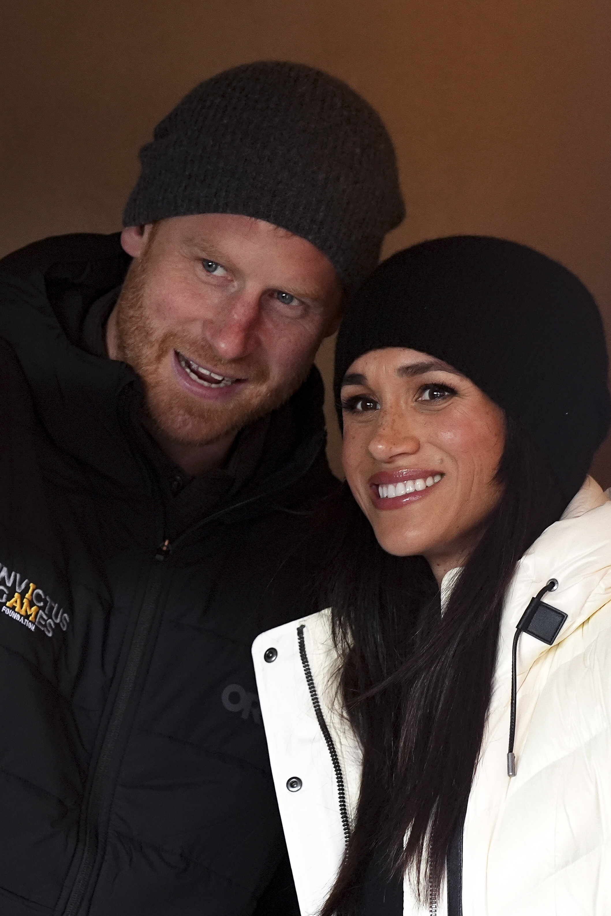 Duke and Duchess of Sussex smiling, while dressed in winter coats and hats