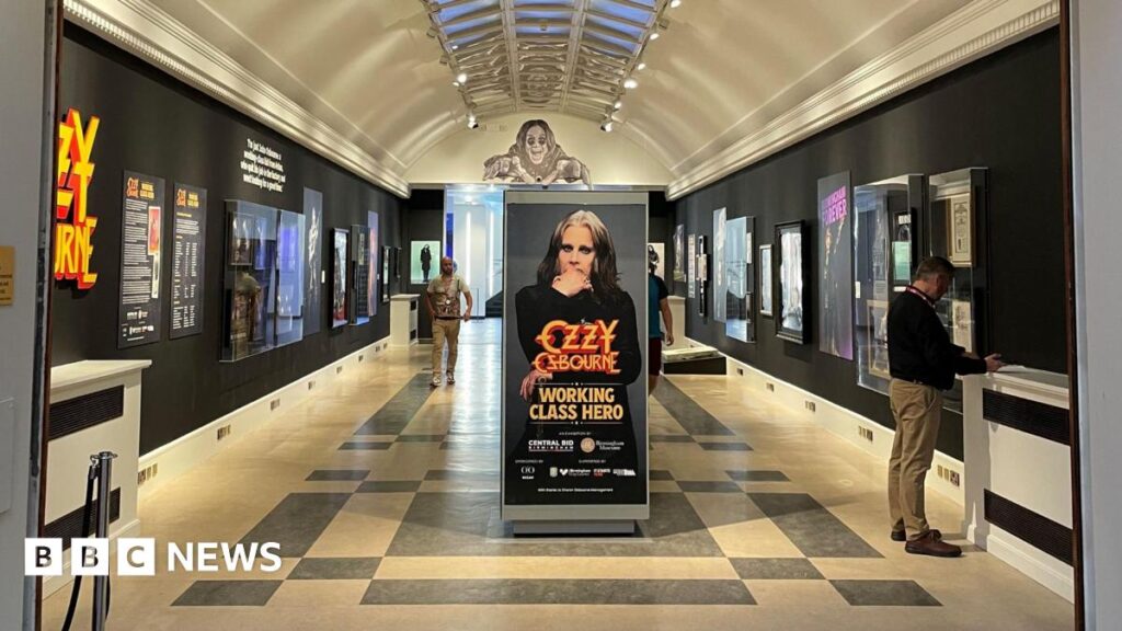 Extra time for Birmingham Ozzy Osbourne exhibition due to demand An art gallery hall with framed pictures on black walls. There is a poster of a man in the centre of the room, which says "Ozzy Osbourne, Working Class Hero" on it.