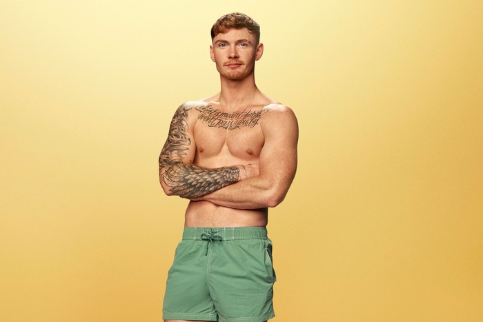 Jack Keating looking ahead with his arms folded in front of him. He is wearing green swim shorts.