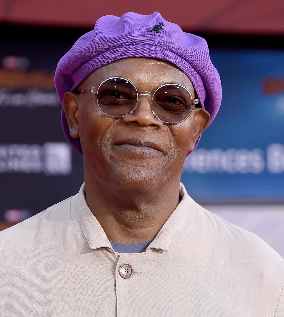 A person in a chic beret and sunglasses, wearing a stylish jacket, attends a public event