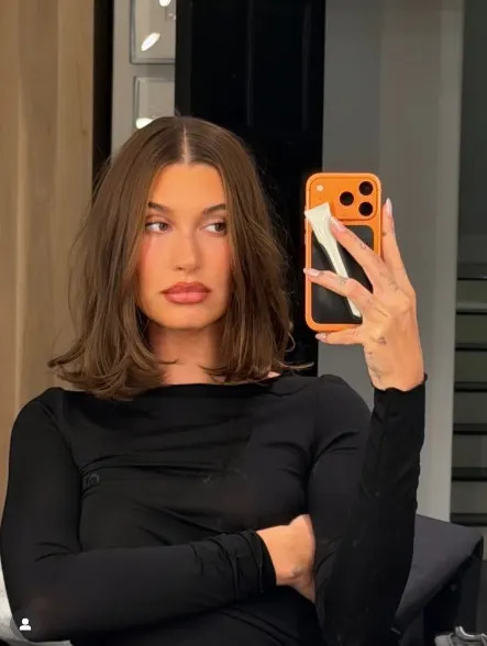 Hailey Bieber wearing a collarbone-grazing lob with a center part and smooth, structured finish.