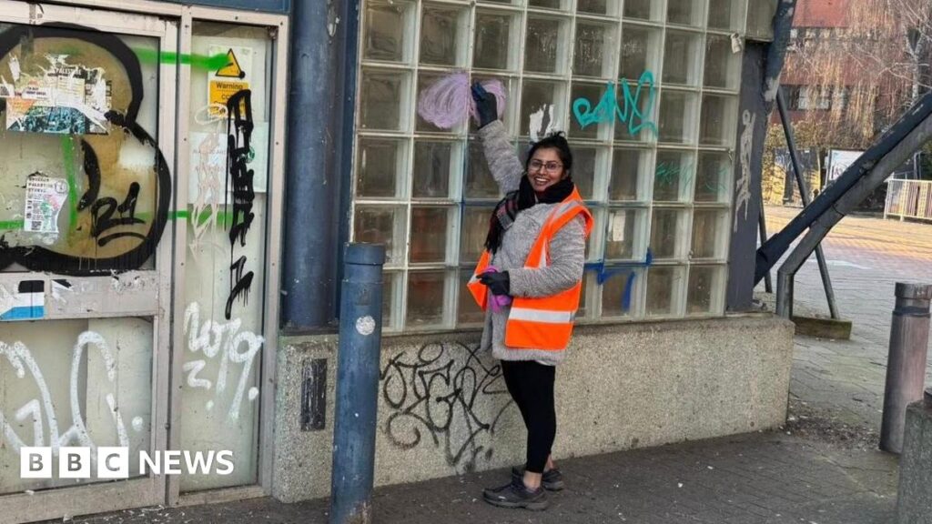Woman cleans graffiti from ‘eyesore’ building in Swindon centre Woman in orange high-vis scrubbing a window on an old brick building covered in graffiti