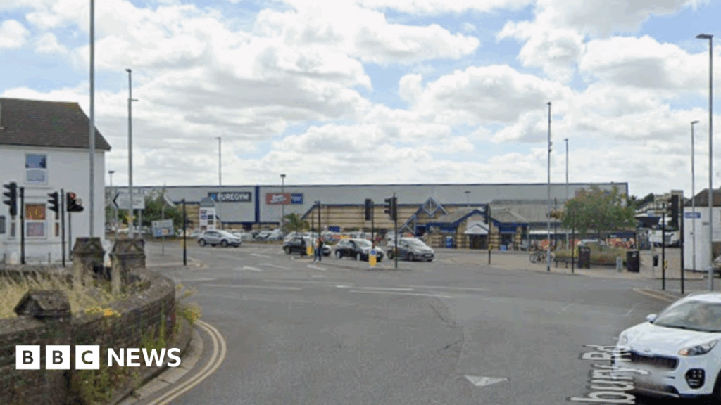 A Google Maps image of the junction with traffic lights, cars and people walking.