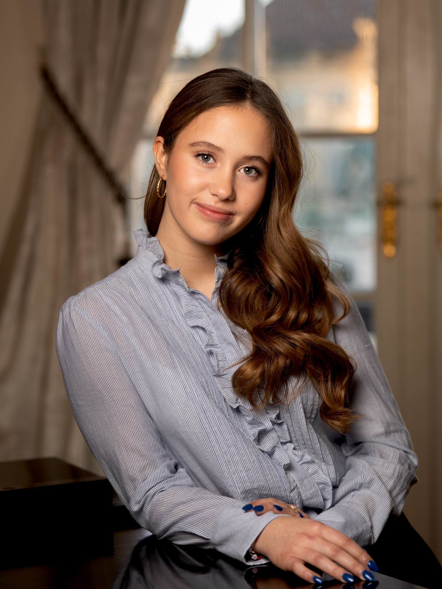 Princess Josephine wearing a blue blouse leaning on a table