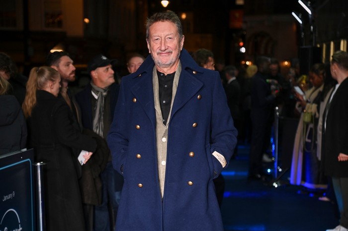 "A Thousand Blows" Season 2 World Premiere - VIP Arrivals Steven Knight, wearing a blue coat and stood on a blue carpet, surrounded by people.