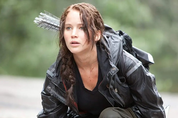 Jennifer Lawrence as Katniss Everdeen in The Hunger Games Jennifer Lawrence as Katniss Everdeen in The Hunger Games crouching with a bow and arrows on her back