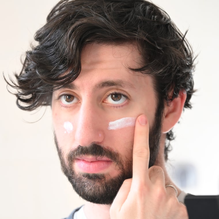 Man applying sunscreen on face.