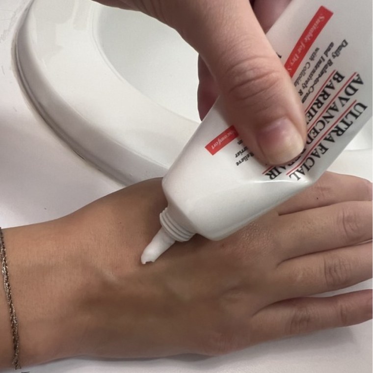 Woman dispensing cream on back of hand