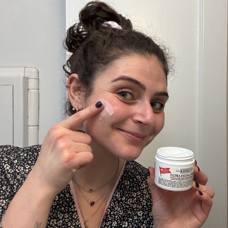 Woman applying cream on face.