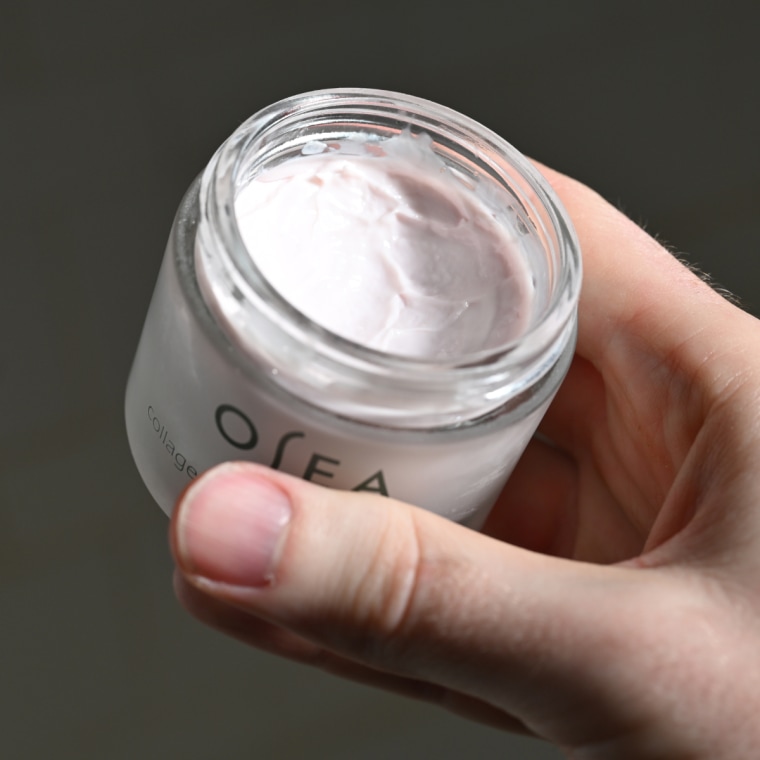 Man holding jar of moisturizer.