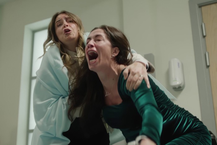 Charity, with a towel around her, wraps her arms over Shona's shoulders in a hospital scene as she cries out in pain. Shona is wearing a velvet green dress in the Corriedale crossover.