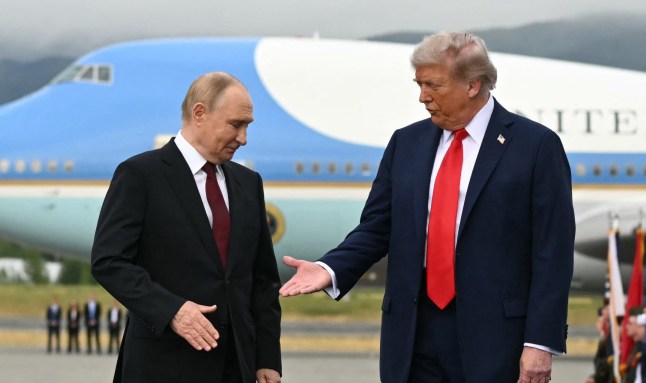 (FILES) US President Donald Trump (R) reaches out to shake hands with Russian President Vladimir Putin as they pose on a podium on the tarmac after arrival at Joint Base Elmendorf-Richardson in Anchorage, Alaska, on August 15, 2025. Donald Trump demolished part of the White House near the end of 2025 to make way for a giant ballroom, a fitting symbol for a president whose second term began like a political wrecking ball. In the second year of his second presidency, Trump's will seek to turn his bulldozer into a lasting legacy. But in politics, as with his construction work, 2026 is going to involve heavy lifting. (Photo by ANDREW CABALLERO-REYNOLDS / AFP via Getty Images)