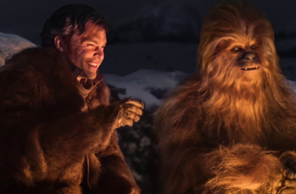 Han Solo laughing with Chewbacca around a campfire