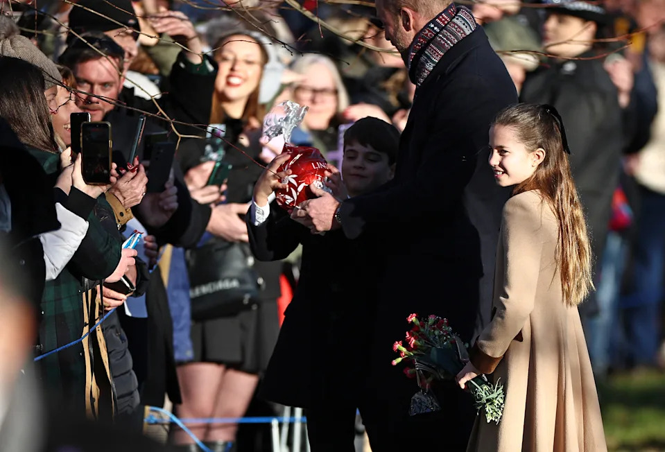 Britain's Prince Louis of Wales reacts with his father Britain's Prince William, Prince of Wales and sister Britain's Princess Charlotte of Wales as he receives a giant chocolate from a well-wisher upon leaving after attending the Royal Family's traditional Christmas Day service at St Mary Magdalene Church on the Sandringham Estate in eastern England, on December 25, 2025. (Photo by HENRY NICHOLLS / AFP via Getty Images)