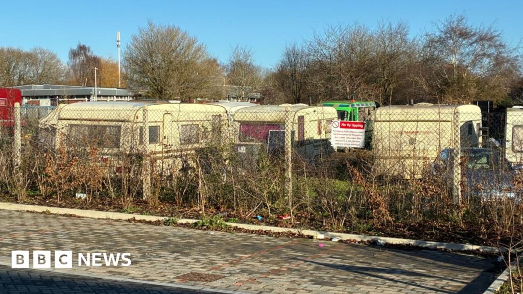 Southmead residents shocked over van-dweller site plans A row of caravans behind a wire fence, with some bushes in the foreground.