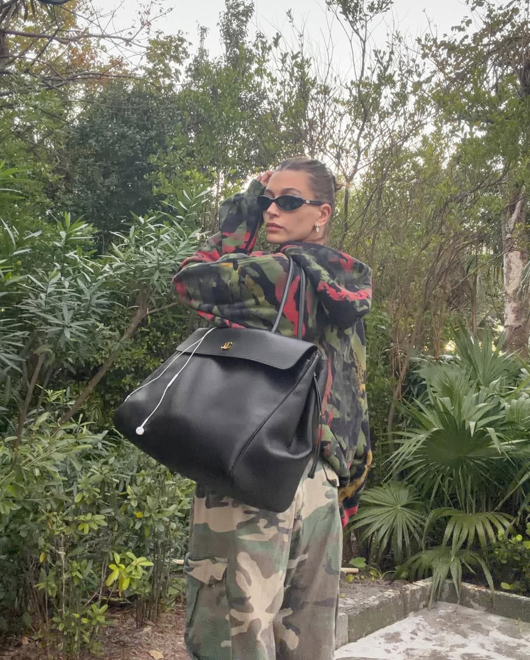 Hailey Bieber shares a new Instagram post wearing a vintage Roberto Cavalli swimsuit, an oversize striped sweater, and carrying a brand new Chanel 2026 tote bag