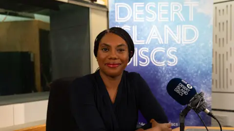 BBC Studios Audio Kemi Badenoch, dressed in black, sitting in the Desert Island Discs studio 