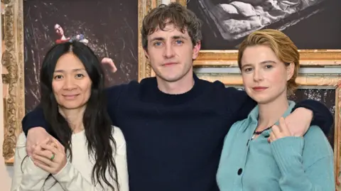 Getty Images Chloé Zhao, Paul Mescal and Jessie Buckley attend a photocall for new exhibition "Hamnet: Even As A Shadow, Even As A Dream" at Tristan Hoare Gallery on December 16, 2025 in London, England