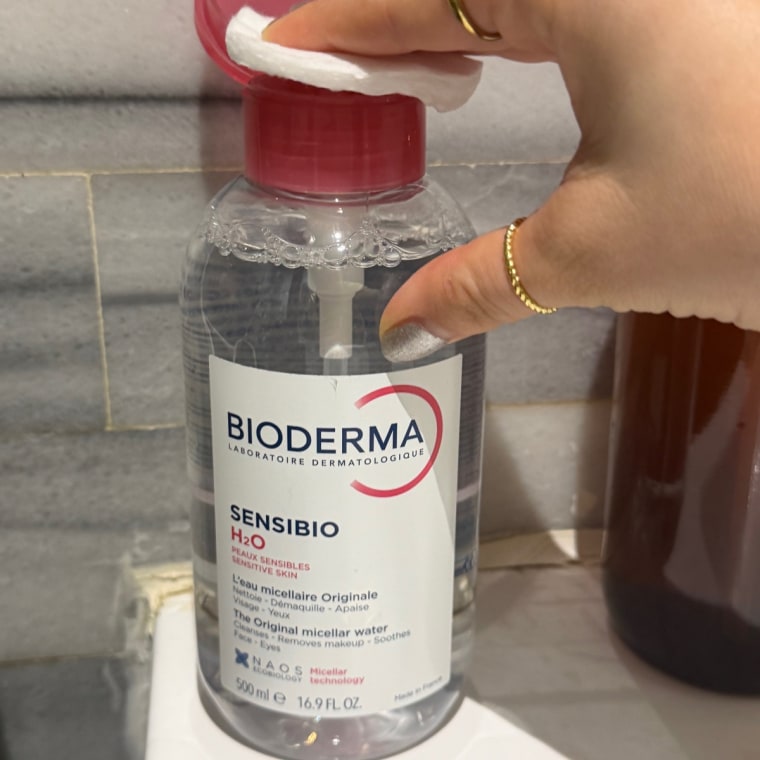 Person putting micellar water on cotton pad