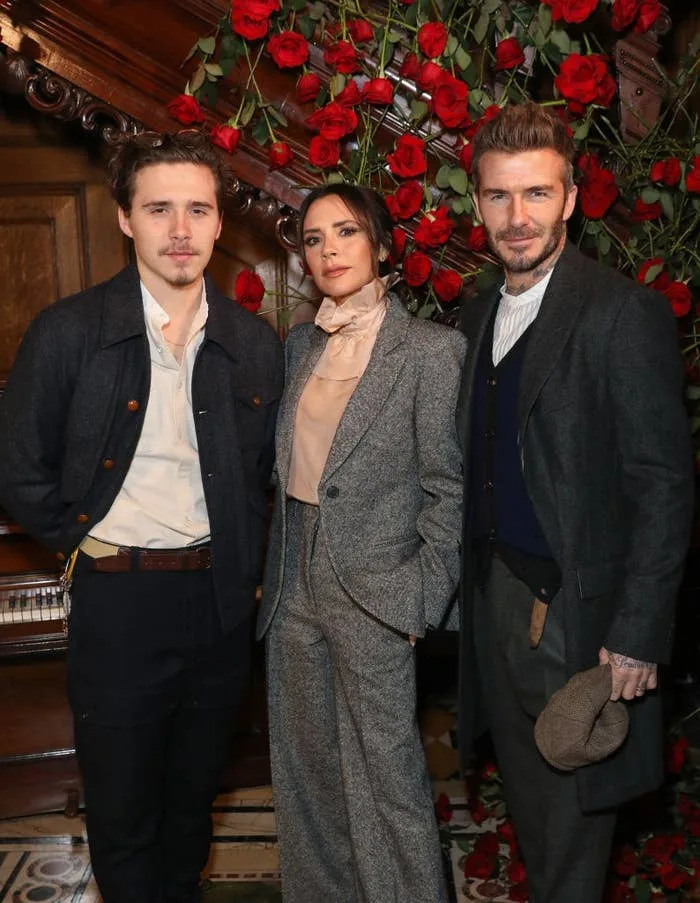 Three people posing in formal attire, standing in front of a backdrop with roses