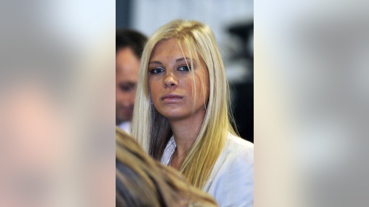 A close-up of Chelsy Davy wearing a white blouse looking downcast.