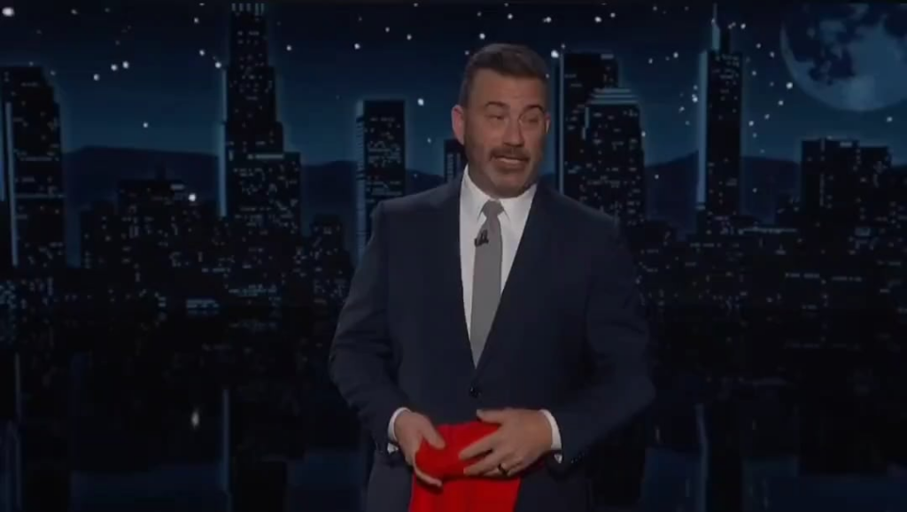 Jimmy Kimmel showing solidarity with the people of Minneapolis after an ICE agent murdered Renee Nicole Good and holding up a 'ICE GET THE F**K OUT OF MPS' shirt