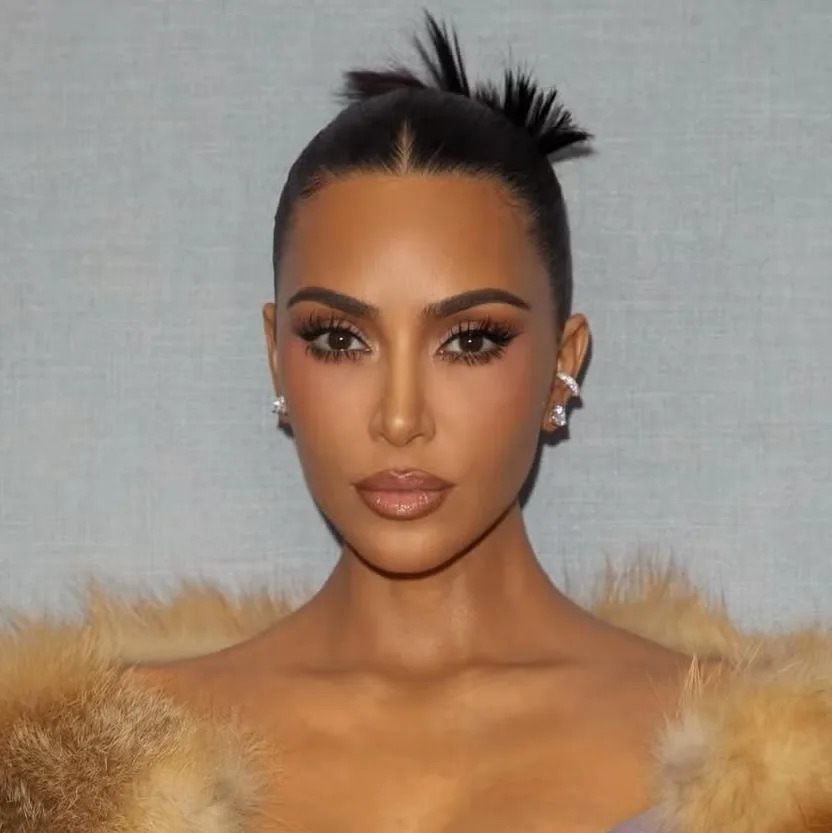 Kim Kardashian wearing a slicked-back updo with a smooth, polished texture and defined hairline.