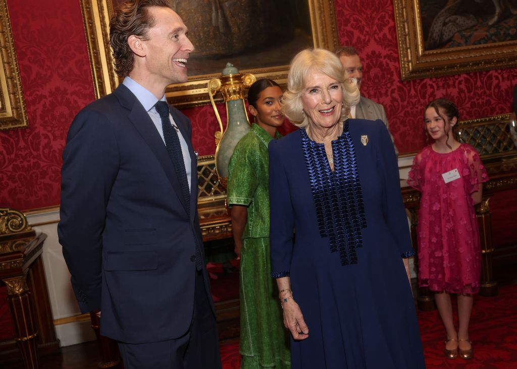  Queen Camilla shares a joke with Tom Hiddleston during a reception for the BBC's 500 Words Finalists at Buckingham Palace on February 28, 2024 in London