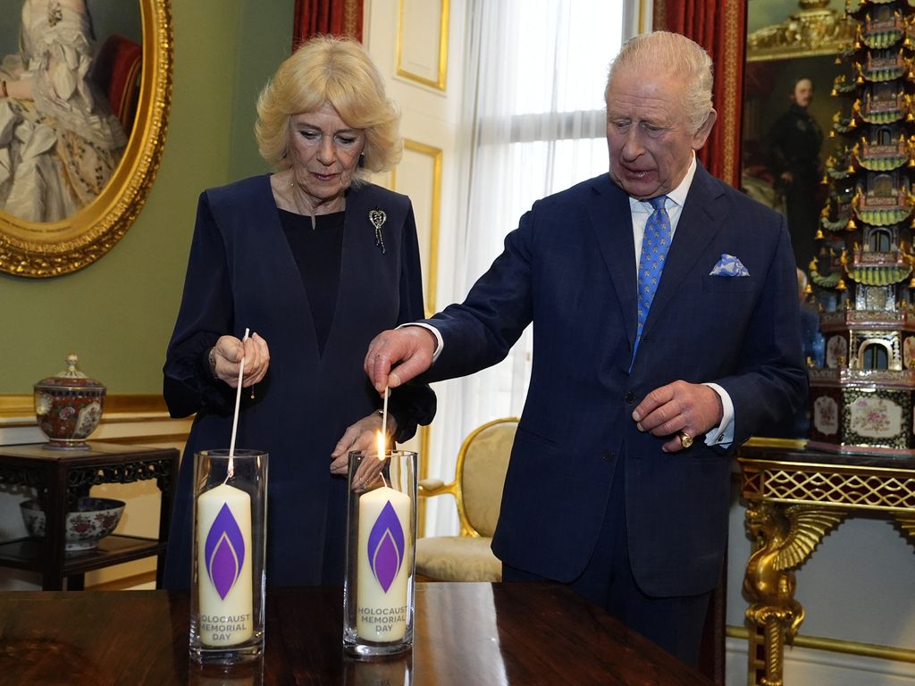 A photo of King Charles and Queen Camilla lighting candles at Buckingham Palace 