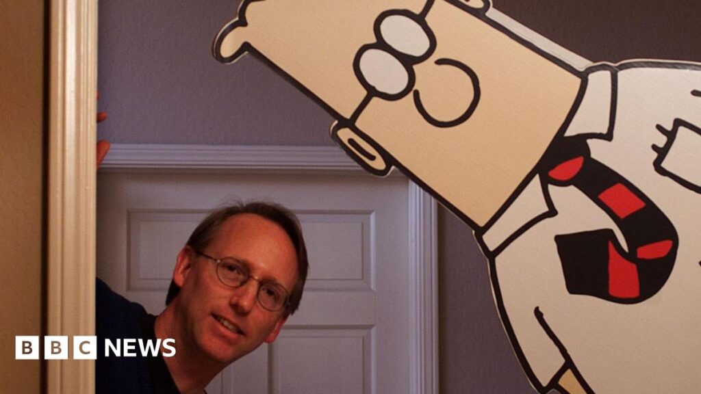 Scott Adams and a cardboard cut-out of Dilbert, both peaking around the corner of a door frame