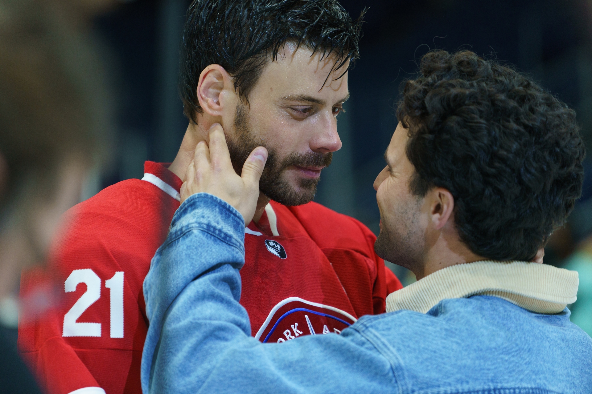 Scott Hunter in a red jersey with number 21 and Kip Grady in a denim jacket looking at each other.