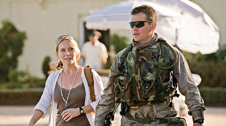 Roy Miller in uniform and sunglasses walks with reporter Lawrie Dayne in 