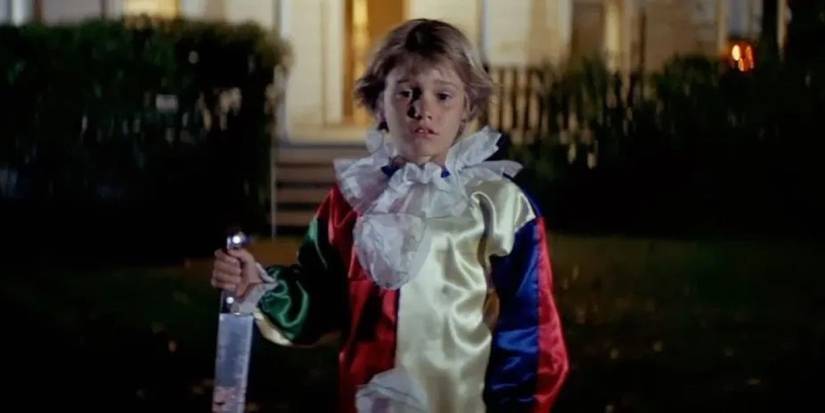 A young Michael Myers (Will Sandlin) dressed as a clown and holding a knife