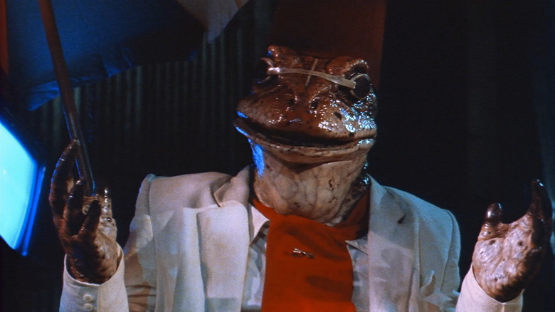Bull (Nicholas Worth) raises his hands wearing a lounge suit in Hell Comes to Frogtown