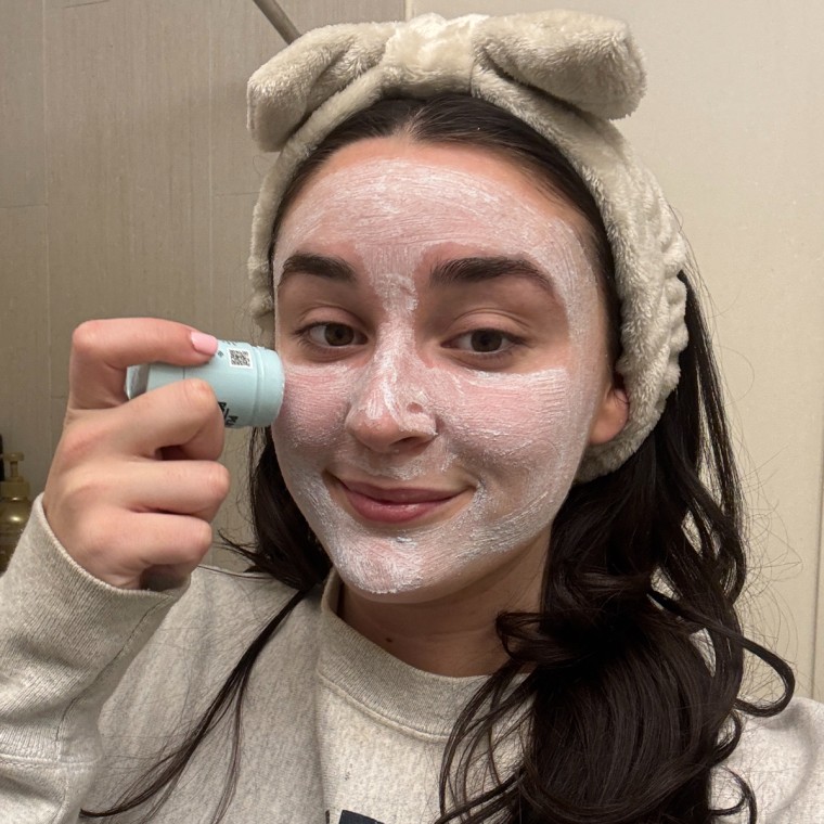Woman applying exfoliating mask on her face