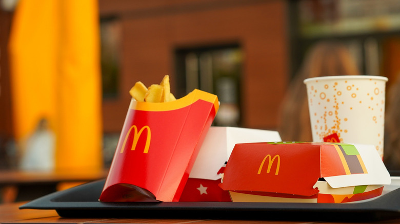 A McDonald's meal featuring fries, burger boxes, and a drink on a black tray