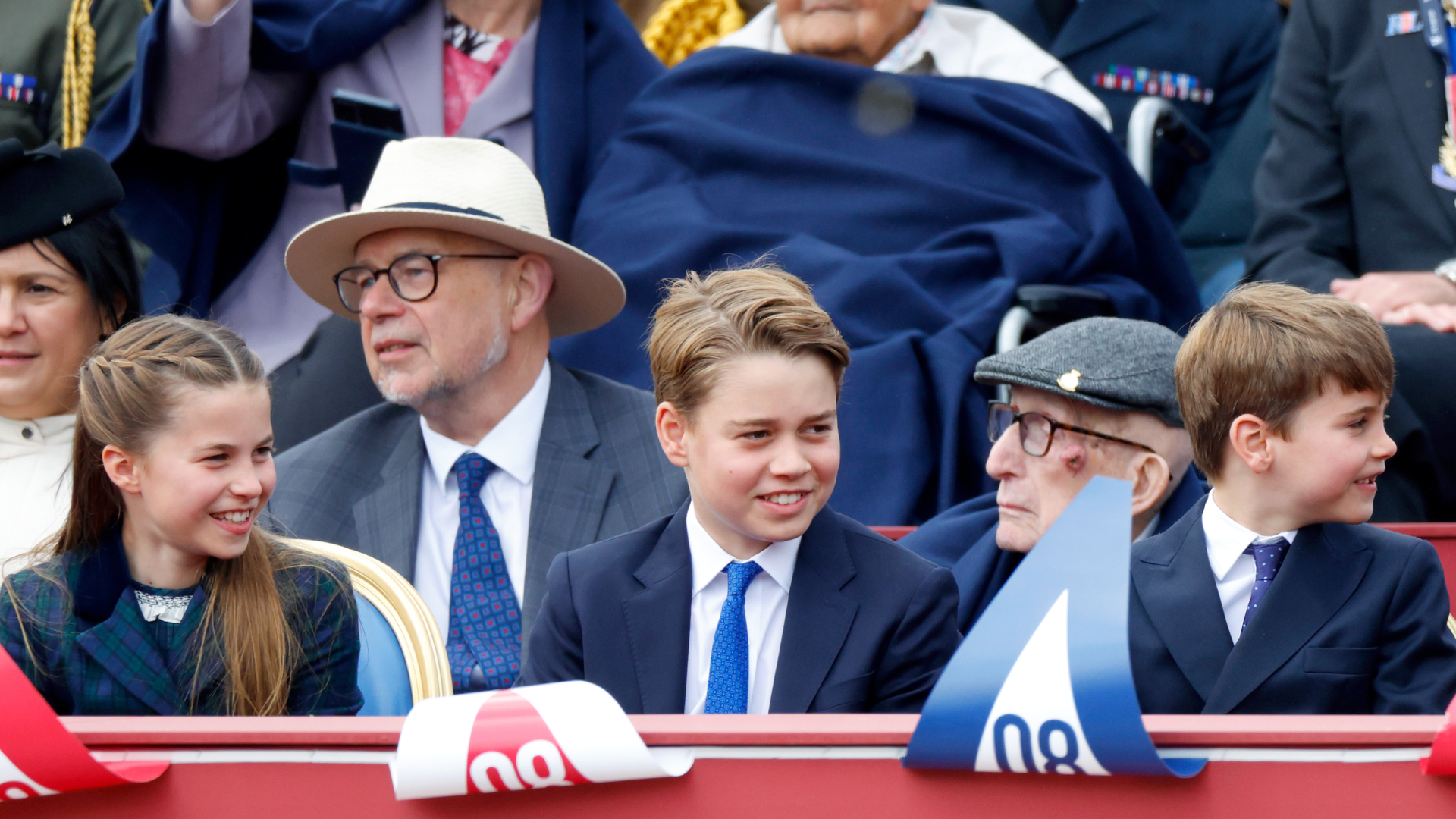Princess Charlotte, Prince George and Prince Louis sitting in a row wearing suits