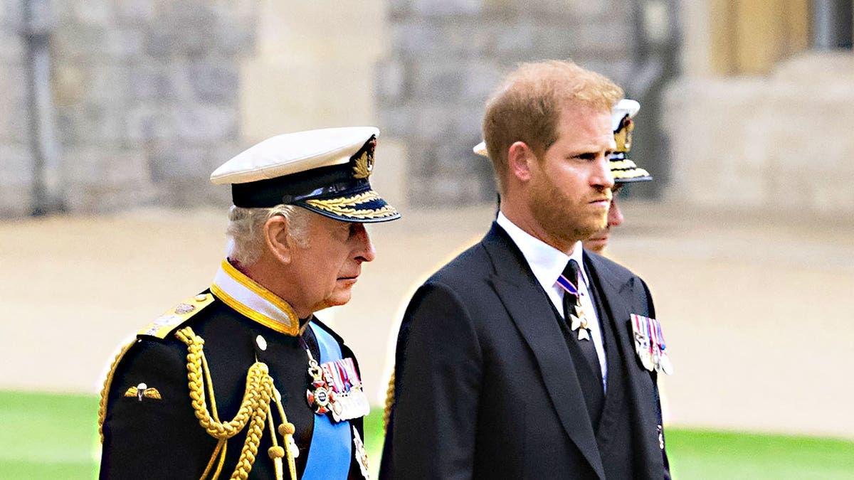 King Charles and Prince Harry walking side-by-side looking somber.