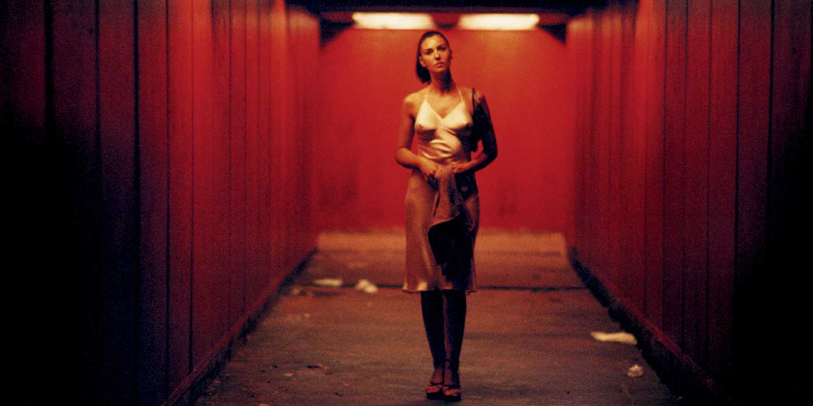 Monica Bellucci as Alex, wearing a white dress and walking down a dimly lit tunnel in Irréversible