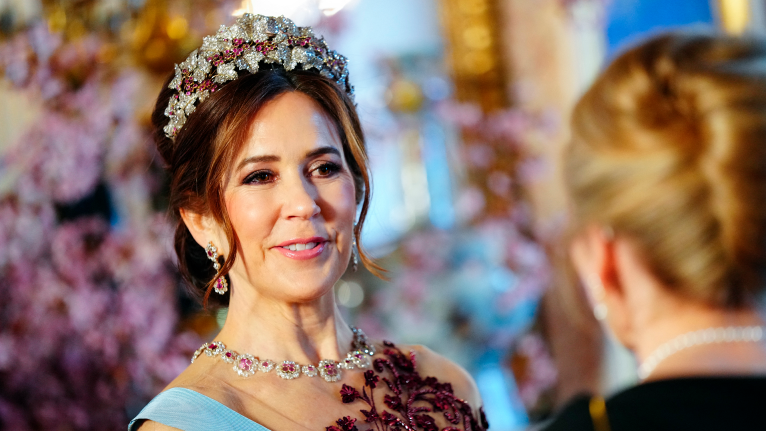 Queen Mary wearing a diamond and ruby tiara and a matching necklace with an embroidered red gown