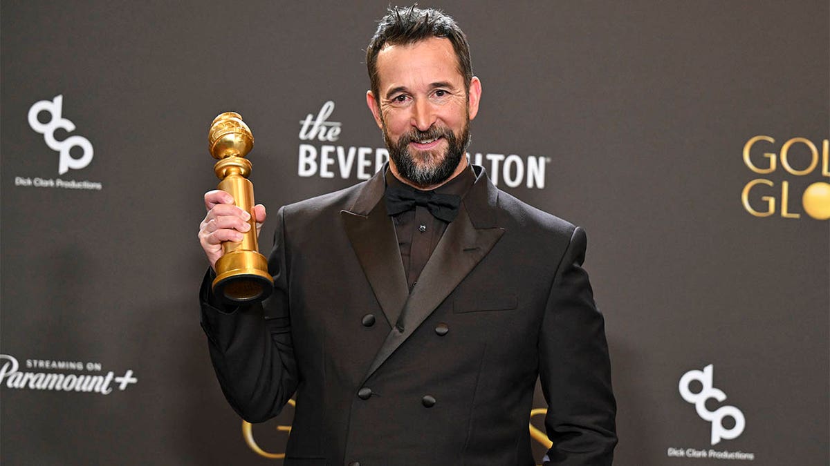 Noah Wyle holding his Golden Globe