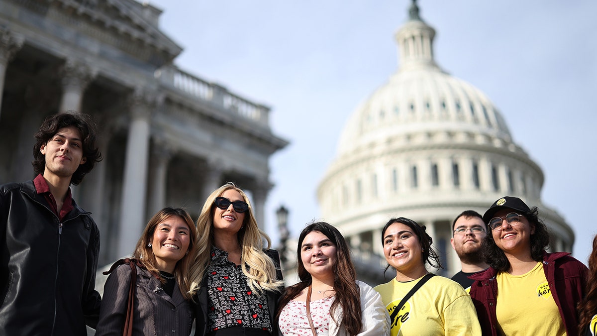 Paris Hilton posing with a group of smiling youth outside Capitol Hill.